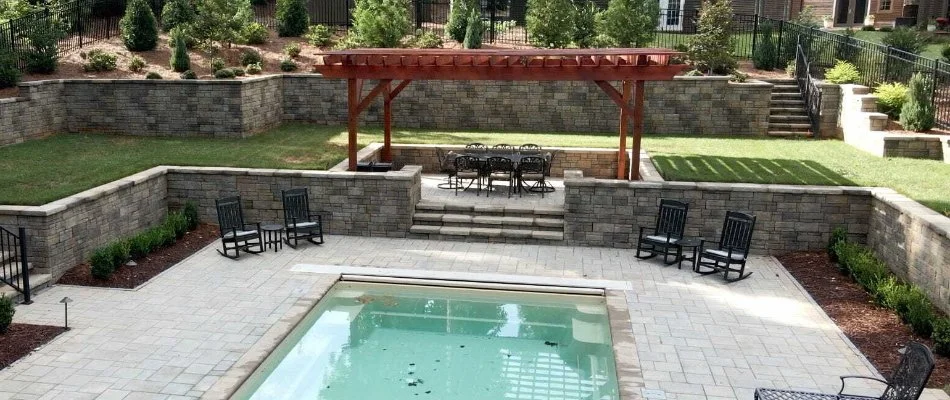 Pergola, patio, and retaining wall beside a pool in an outdoor space in Governors Club, NC.